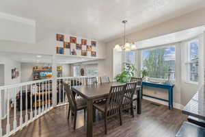 Dining area featuring wood finished floors, a textured ceiling, a healthy amount of sunlight, and an inviting chandelier