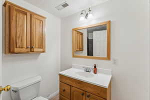 Bathroom featuring baseboards, visible vents, toilet, and vanity