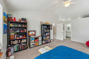 Bedroom featuring ceiling fan, carpet floors, baseboards, ensuite bath, and lofted ceiling