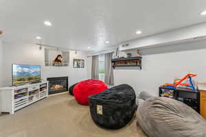 Interior space with a glass covered fireplace, visible vents, recessed lighting, carpet floors, and rail lighting