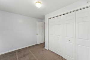 Unfurnished bedroom with carpet floors, a closet, and baseboards