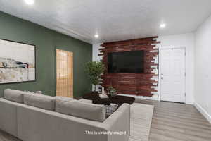Staged Living area featuring slat wall for TV, wood finished floors, recessed lighting, and a textured ceiling