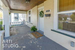 View of exterior entry featuring covered porch and brick siding