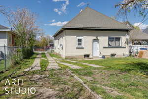 Rear view of property featuring fence, a lawn, a shingled roof, and brick siding