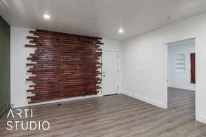 Empty room featuring baseboards, wood finished floors, a textured ceiling, and recessed lighting
