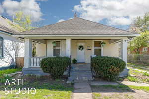 Bungalow-style home featuring brick siding, roof with shingles, a porch, and fence