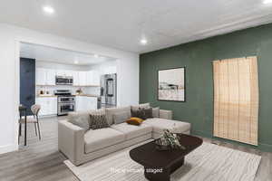 Staged open concept Living area featuring light wood-style flooring, baseboards, and recessed lighting
