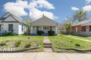 View of front of property with roof with shingles, a front lawn, a  covered porch, and fence
