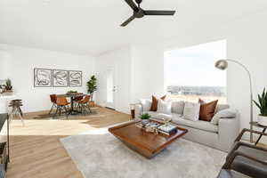 Living area with light wood finished floors, a ceiling fan, and baseboards