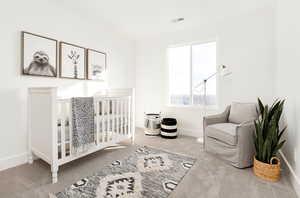 Carpeted bedroom with baseboards, visible vents, and a crib