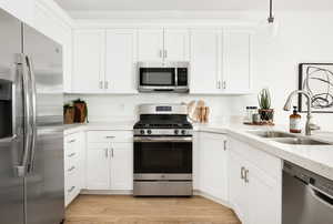 Kitchen featuring a sink, appliances with stainless steel finishes, and white cabinetry