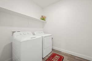 Laundry room featuring baseboards, light wood-type flooring, laundry area, and independent washer and dryer
