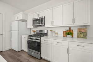 Kitchen featuring white cabinetry, stainless steel appliances, dark wood-style flooring, and light countertops