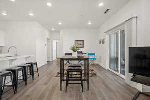 Dining space featuring visible vents, light wood-style flooring, and baseboards