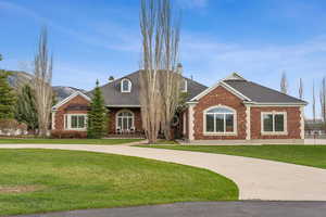 View of front of home with a front lawn, a mountain view, a chimney, and brick siding