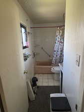Full bath featuring tile patterned floors, shower / tub combo with curtain, and toilet