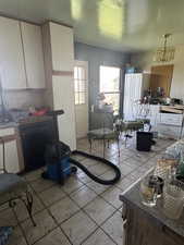 Kitchen featuring white cabinets, a chandelier, light tile patterned flooring, dishwasher, and backsplash