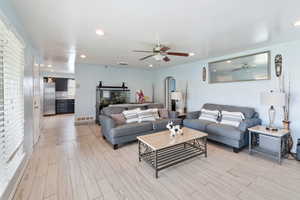 Living room with arched walkways, visible vents, ceiling fan, and light wood-style floors