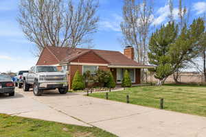 Ranch-style home with driveway, a chimney, and a front lawn