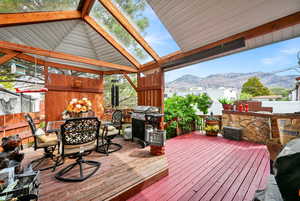 Wooden deck featuring fence, outdoor dining space, area for grilling, and a mountain view
