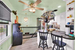 Kitchen with tasteful backsplash, a breakfast bar, light wood finished floors, white cabinetry, and a peninsula