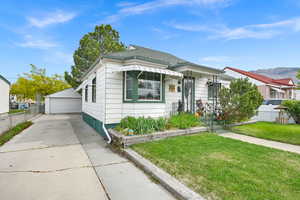 View of front facade featuring fence, an outdoor structure, a detached garage, and a front lawn