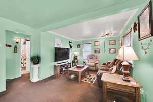 Living area with baseboards, dark colored carpet, and ornamental molding