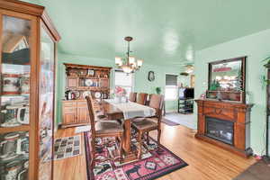 Dining room with a glass covered fireplace, a chandelier, light wood-type flooring, and baseboards