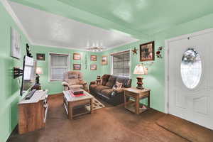 Living area with dark carpet, crown molding, and baseboards