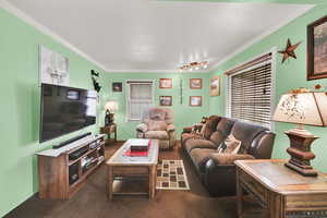 Carpeted living room featuring track lighting, ornamental molding, and baseboards