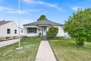 View of front facade with roof with shingles and a front yard