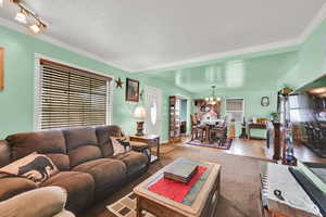 Living area with a chandelier, wood finished floors, and crown molding