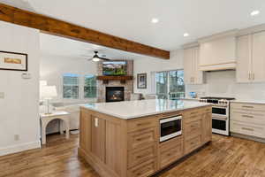 Kitchen featuring double oven range, plenty of natural light, a large fireplace, light countertops, and built in microwave