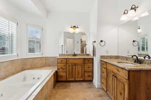 Bathroom featuring a jetted tub, a wealth of natural light, and a sink