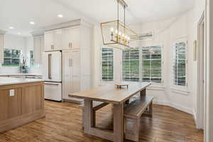 Dining space with a wealth of natural light, an inviting chandelier, and light wood-style flooring