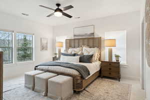 Bedroom with visible vents, ceiling fan, light colored carpet, and baseboards