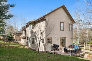 Rear view of house featuring stucco siding, fence, a lawn, and an outdoor hangout area