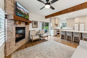 Living room with ceiling fan, beam ceiling, light wood-type flooring, recessed lighting, and a fireplace