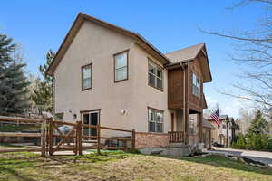 View of side of home with a gate, fence, stucco siding, and a lawn