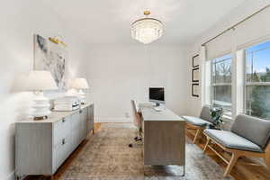 Office area featuring a chandelier and dark wood-style floors
