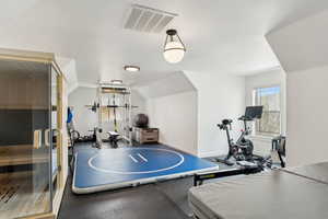 Exercise room with visible vents, lofted ceiling, and baseboards