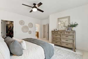 Bedroom featuring a spacious closet, a ceiling fan, and light colored carpet