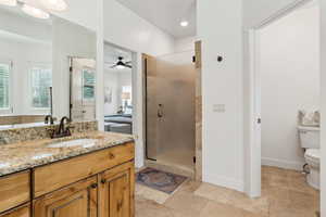 Full bathroom featuring a shower stall, vanity, ceiling fan, toilet, and baseboards