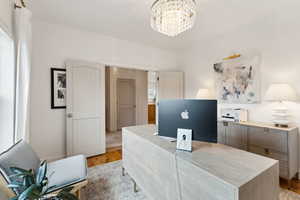 Office area featuring a chandelier and light wood-style flooring