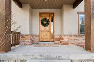 Entrance to property with stone siding and stucco siding