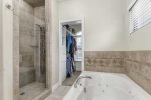 Full bathroom with a tub with jets, a stall shower, tile patterned floors, and a spacious closet