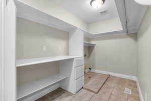 Washroom with light tile patterned flooring, laundry area, electric dryer hookup