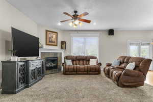 Carpeted living room featuring a tile fireplace, a healthy amount of sunlight, a ceiling fan, and recessed lighting