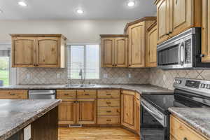 Kitchen with recessed lighting, a sink, light wood-style flooring, backsplash, and appliances with stainless steel finishes