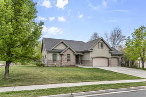 Craftsman-style home featuring stucco siding, a front yard, concrete driveway, and stone siding